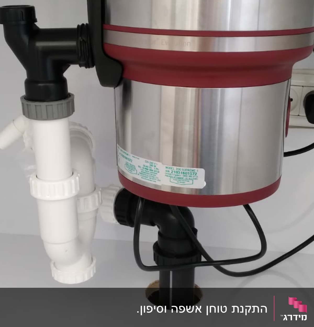 מכשיר טוחן אשפה מתחת לכיור עם צינורות חיבור